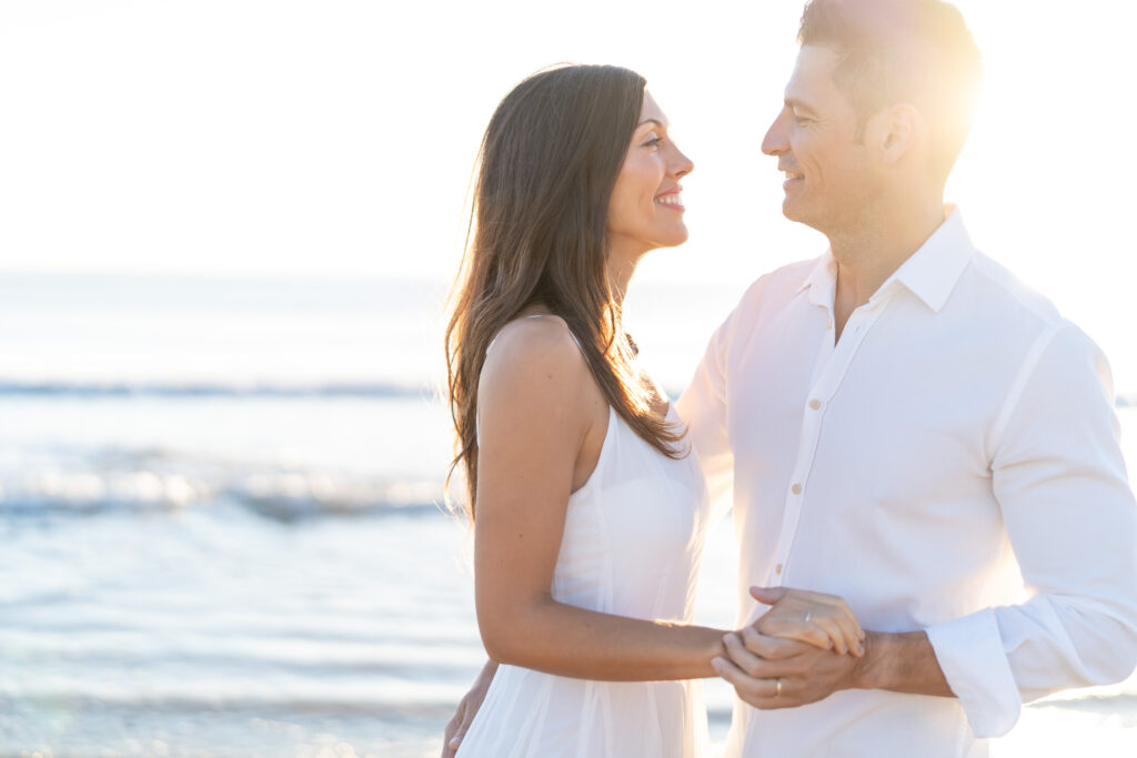 Hombre y mujer tomados de la mano y caminando juntos en La Patacona, Valencia, con el sol de la mañana iluminando su conexión.
