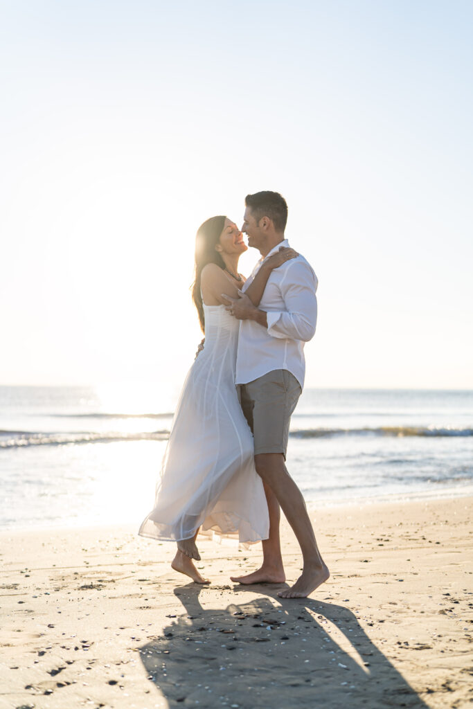 Pareja mirándose a los ojos y sonriendo en La Patacona, Valencia, con el sol de la mañana iluminando su amor.