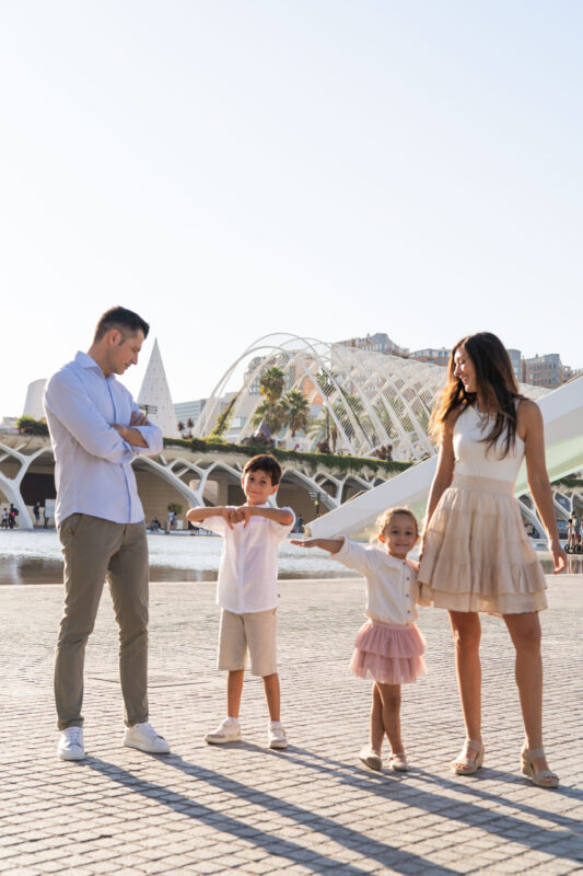 Padres e hijos interactuando naturalmente durante una sesión fotográfica familiar en Valencia, al final de la tarde.