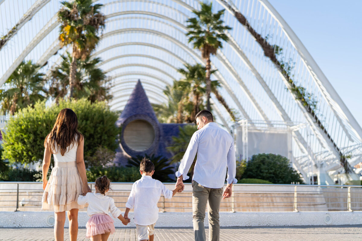 Sesión fotográfica familiar en la Ciudad de las Artes y las Ciencias, Valencia, capturando la conexión y alegría de padres e hijos al atardecer.